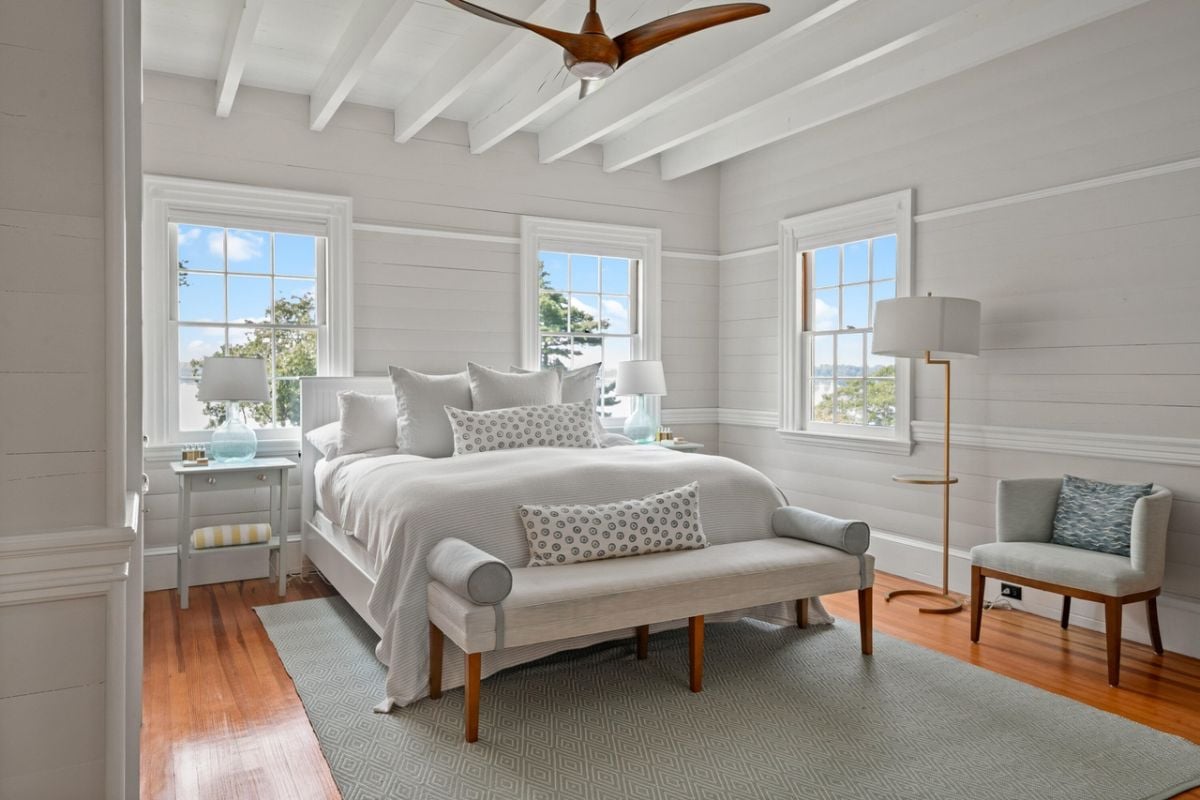Bedroom with a large bed, glass windows, large rug and a vaulted ceiling.