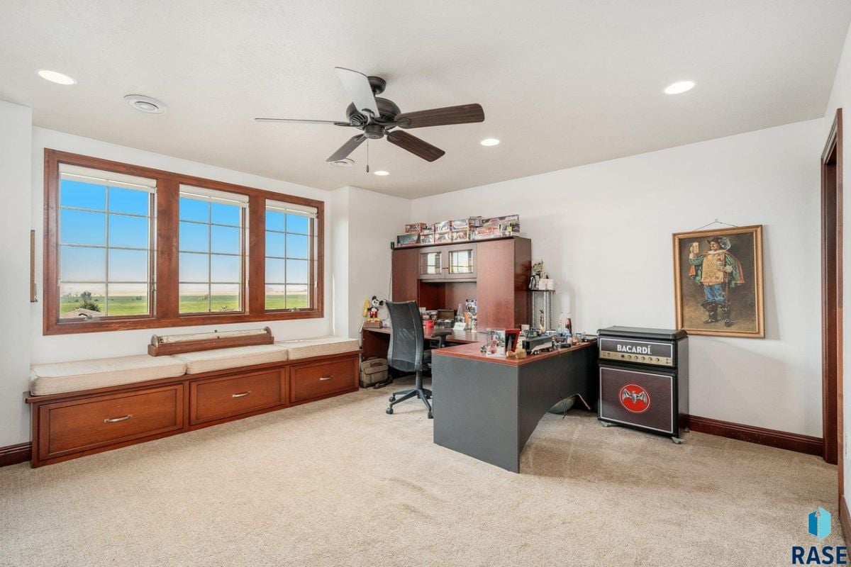 Home office with a desk, chair and carpet flooring.