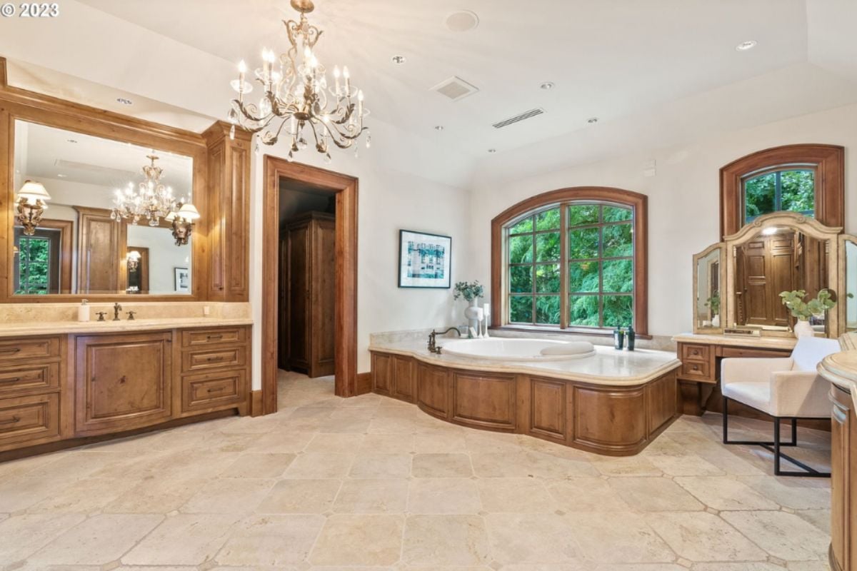 Bathroom with soaking tub, sink, custom cabinet, and chandelier.