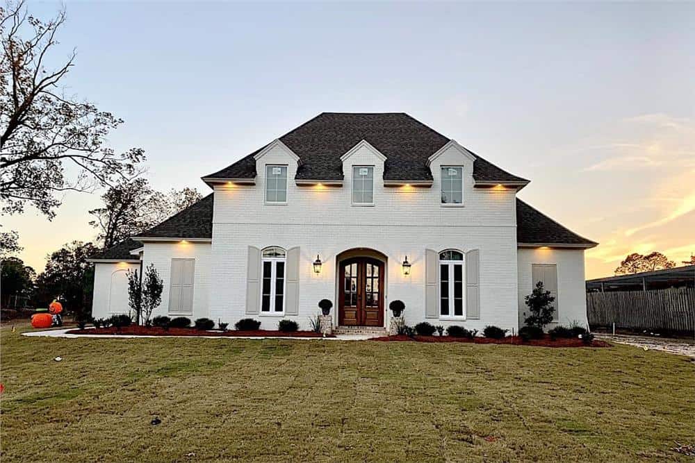 Front view with hipped rooflines, three dormers, and an arched entry.