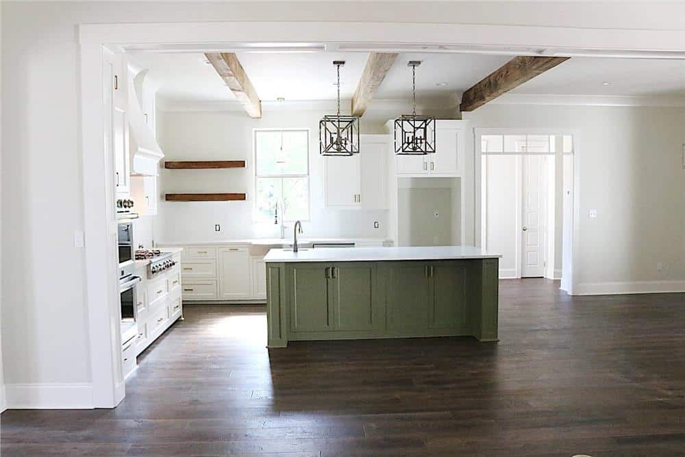 Kitchen with white cabinetry, a center island, and a couple of pendants hanging from the beamed ceiling.