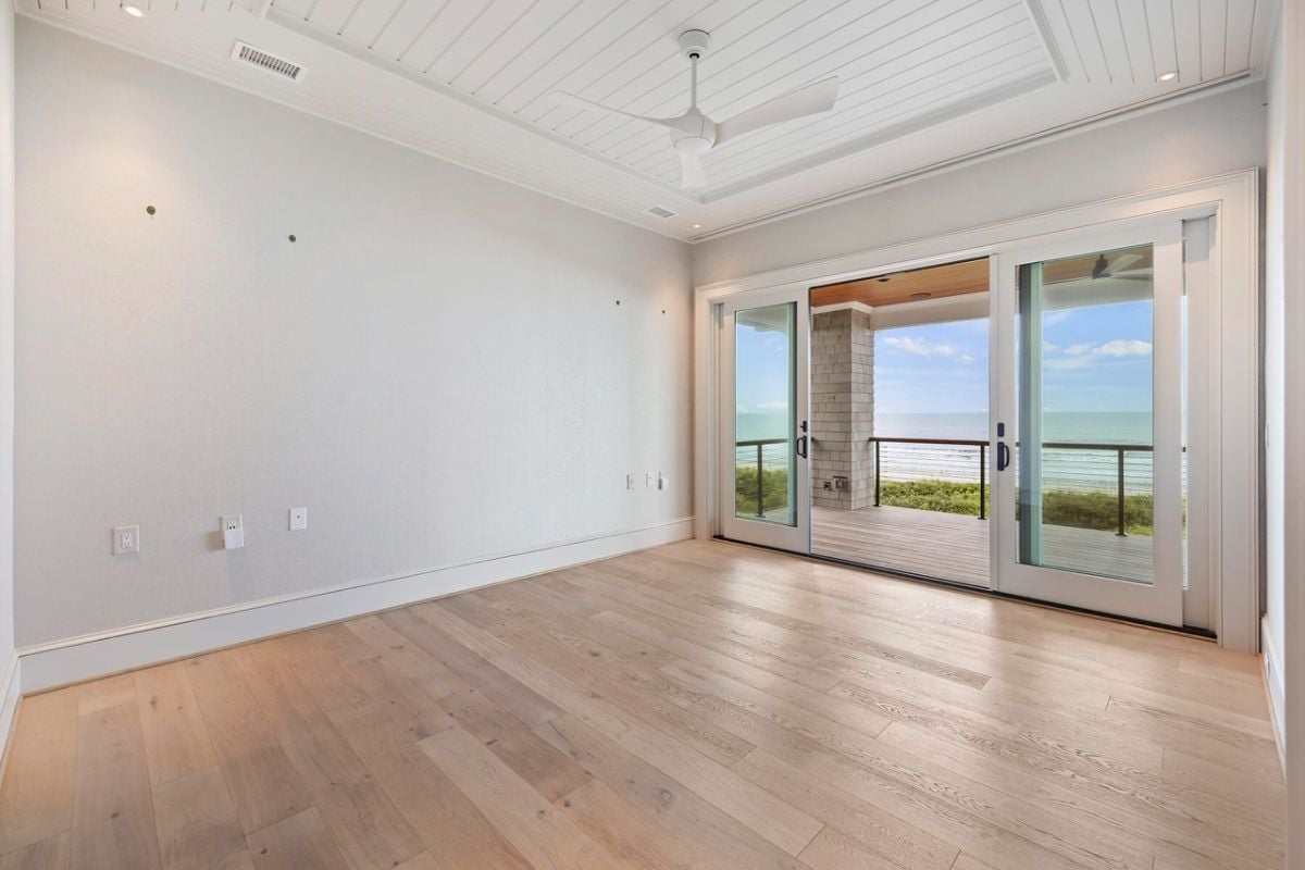 Bedroom with wood flooring, a ceiling fan and glass doors.