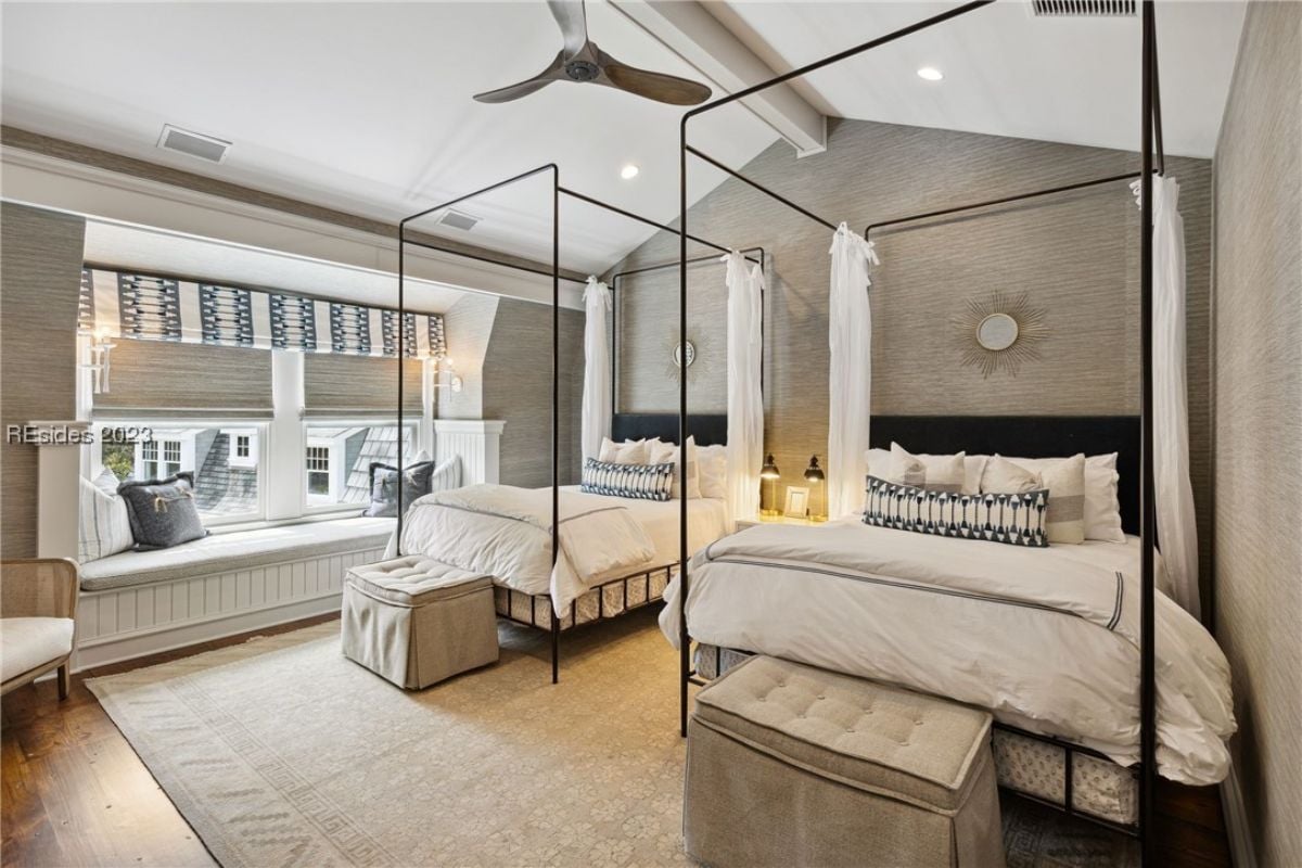 Bedroom with twin beds, ceiling fan, wood flooring and glass windows.