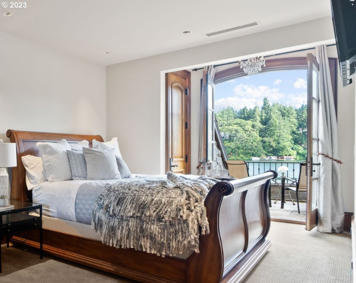 Bedroom with large bed, TV, chandelier and a balcony.