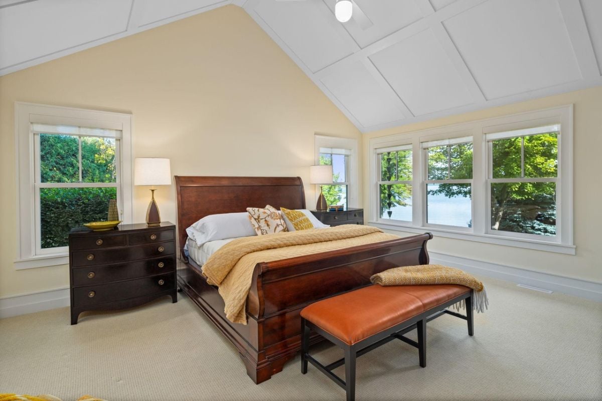 Bedroom with a large bed, carpet flooring and glass windows.