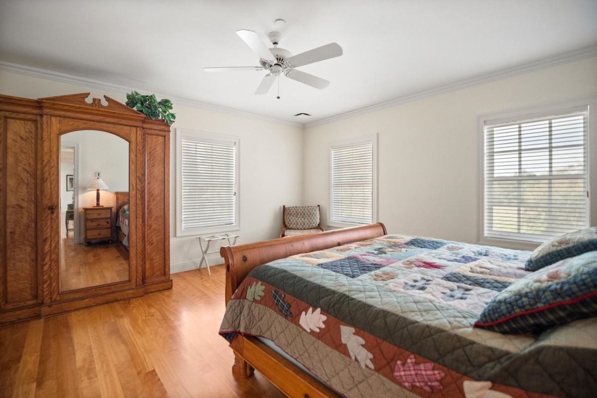 Bedroom with a large bed, ceiling fan, and glass windows.