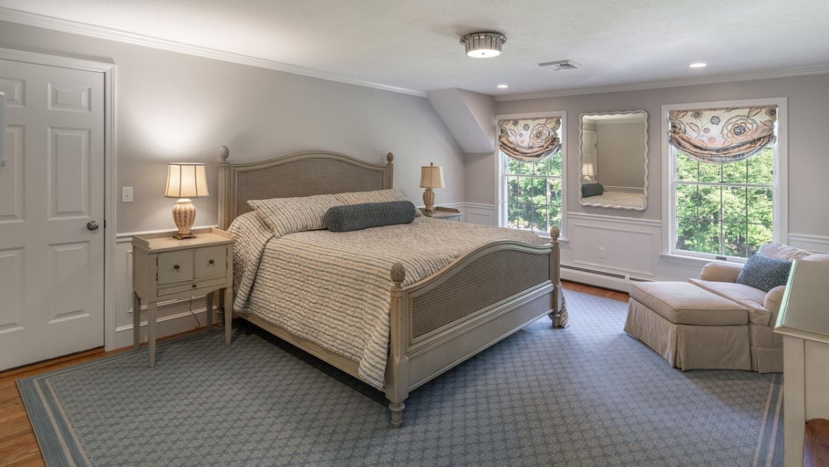 Bedroom with a large bed, custom lights, glass windows and a large rug.