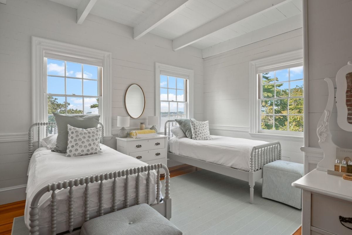 Bedroom with twin beds, glass windows, rug and vaulted ceiling.