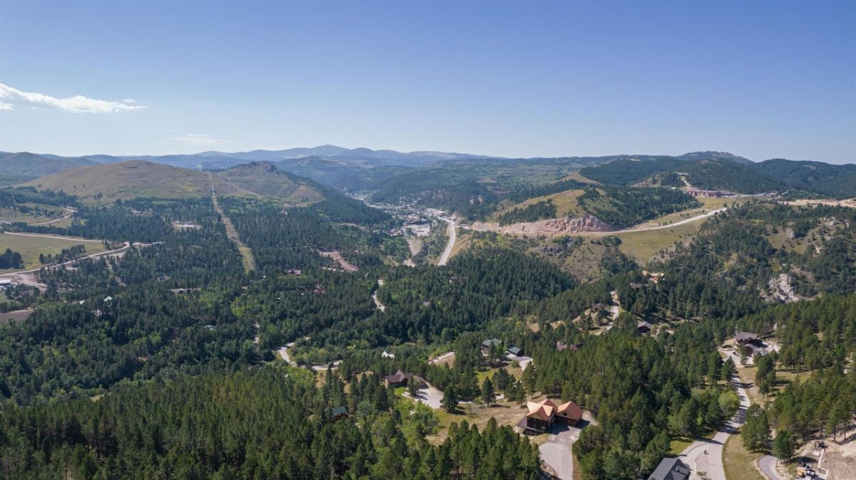 Aerial view of the house with nearby residences and a view of the mountains.