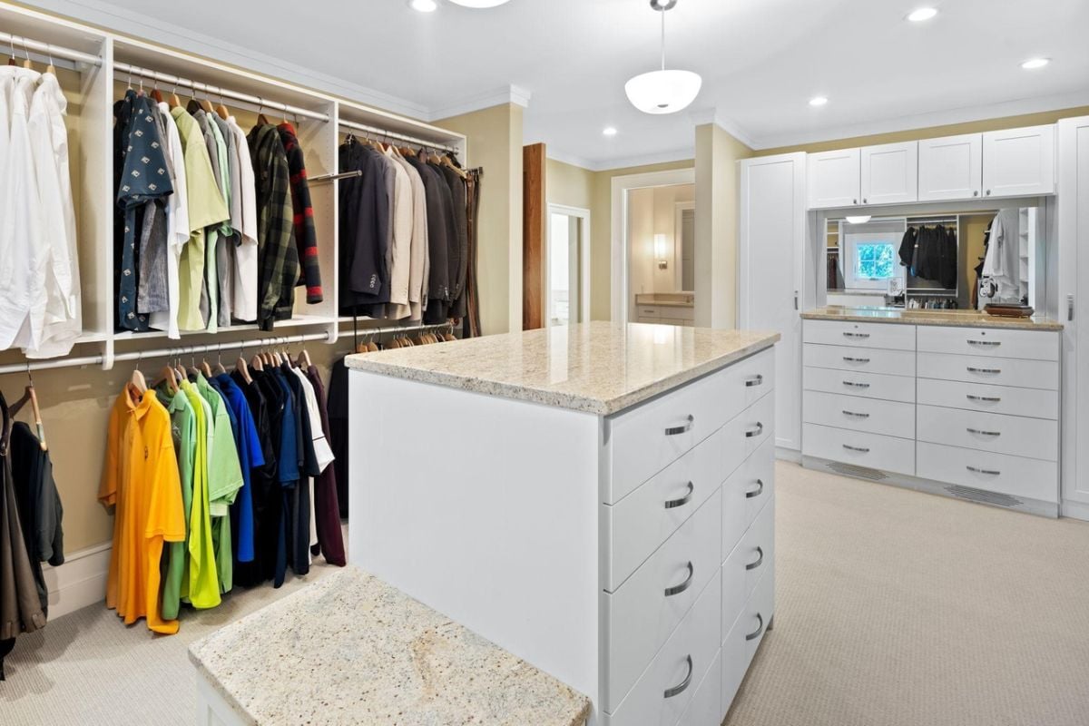 Walk-in closet with a center island, shelves and drawers.