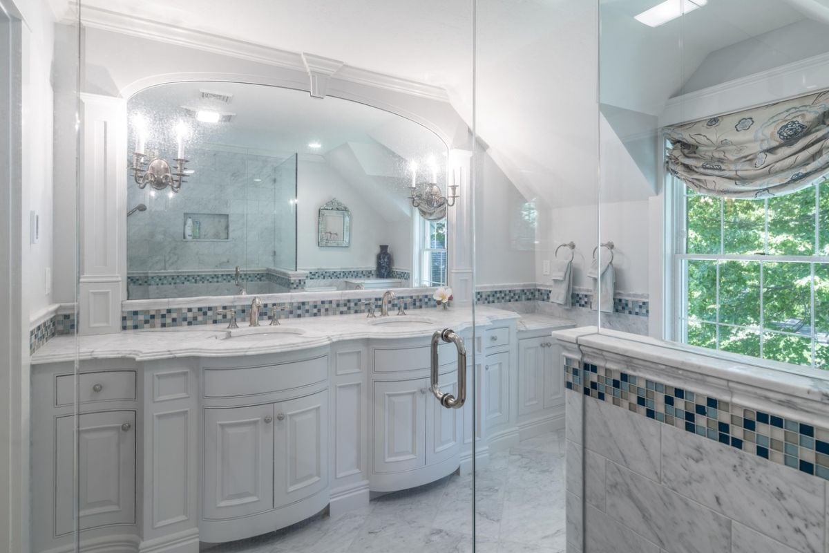 Bathroom with dual sinks, mirror, custom lights and glass windows.