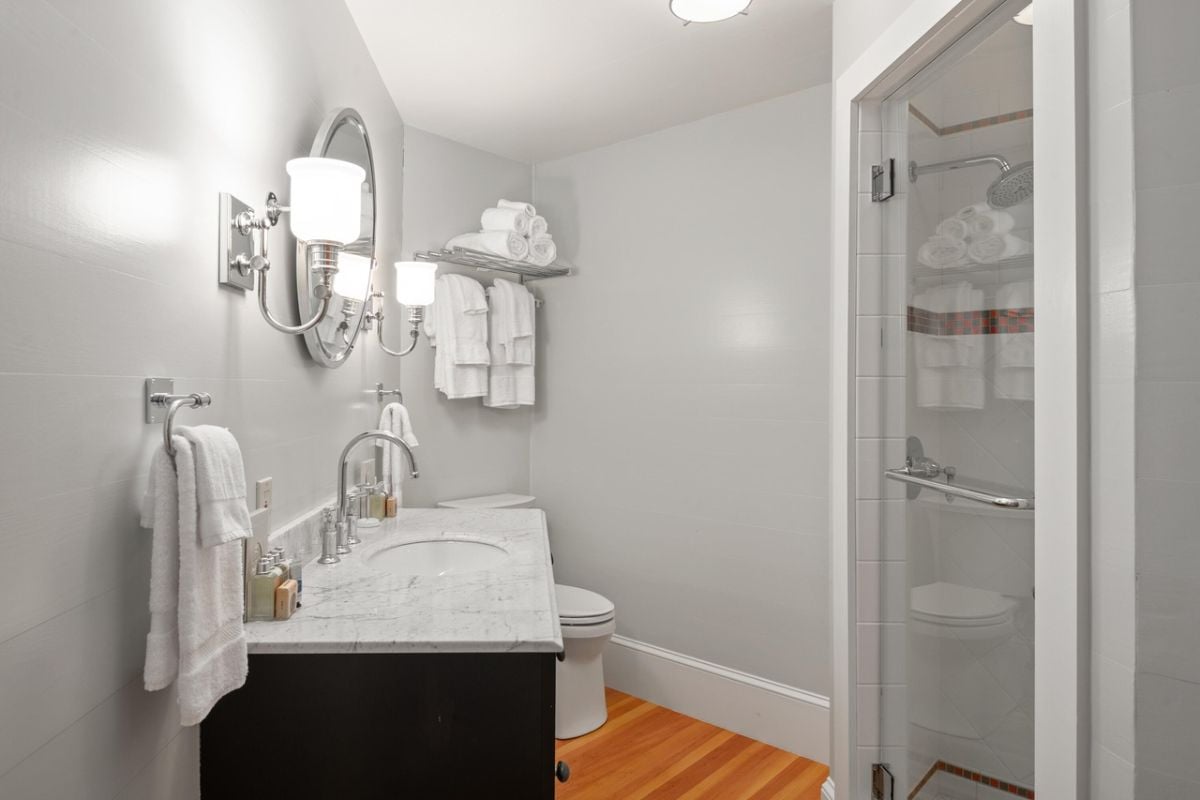 Bathroom with a toilet, sink, walk-in shower and a mirror.