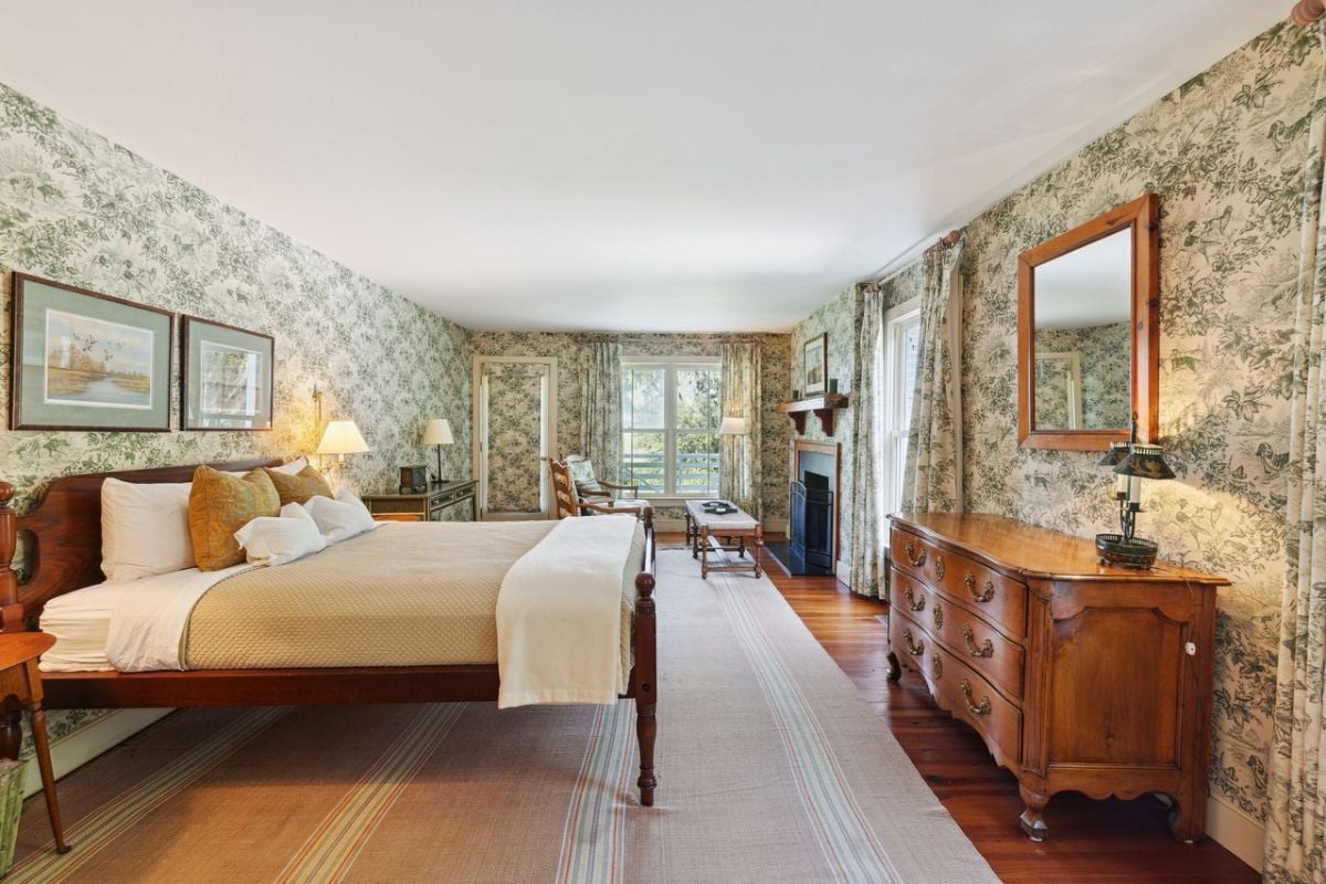 Bedroom with a large bed, wood flooring, and glass windows.