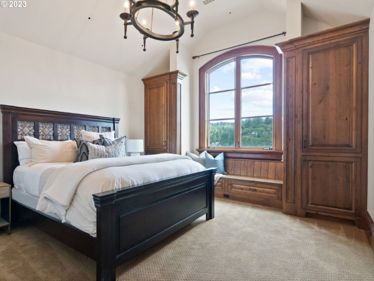 Bedroom with large bed, carpet flooring and glass windows.