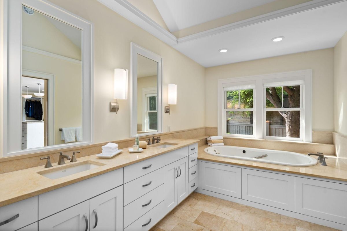 Bathroom with dual sinks, mirrors and a soaking tub.
