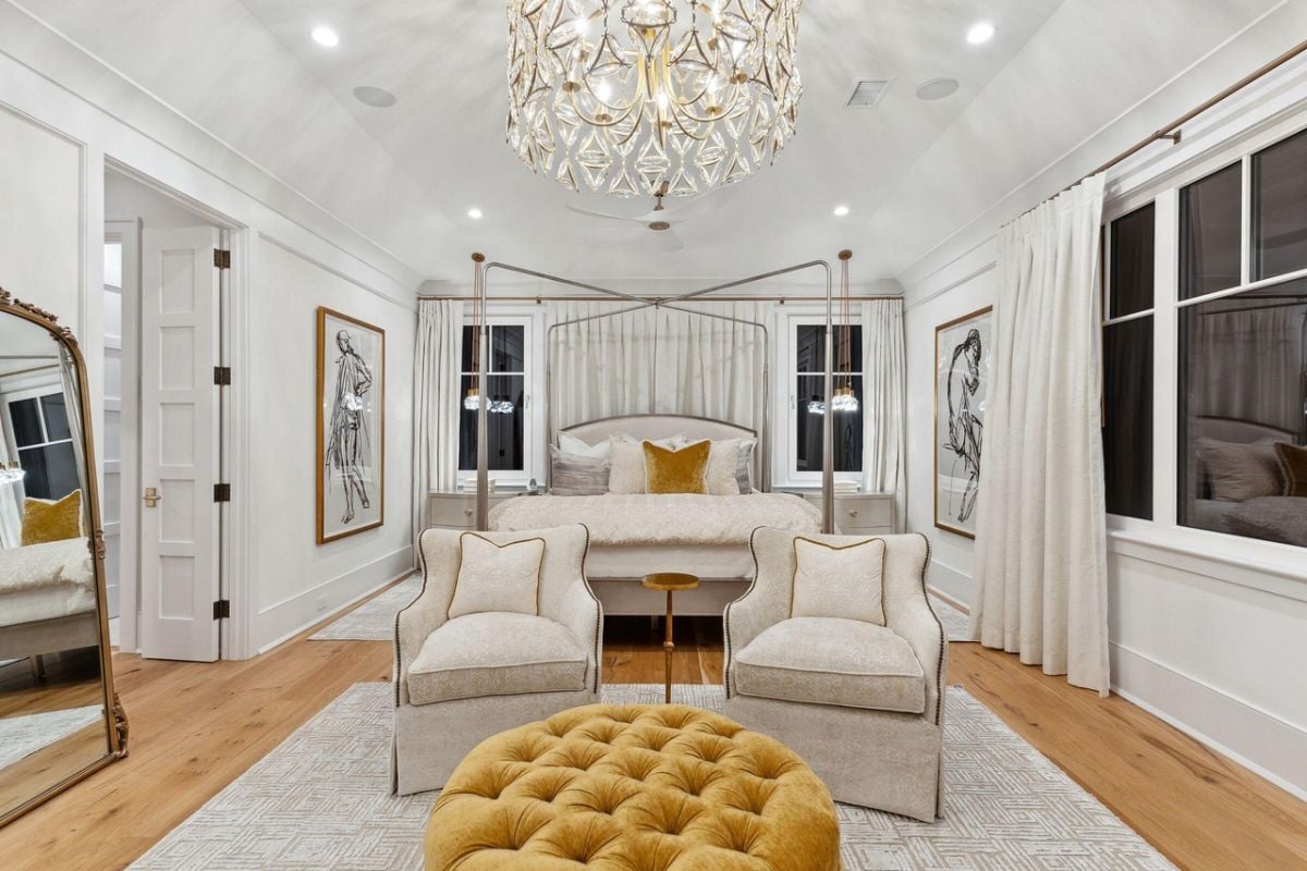 Bedroom with a large bed, wood flooring, chandelier and glass windows.