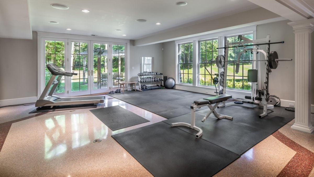 Home gym with workout equipment, workout mats, custom lights and glass walls.