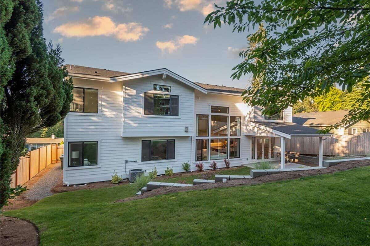 Rear view of the house with huge windows and a covered porch crowned with a sloped roof.