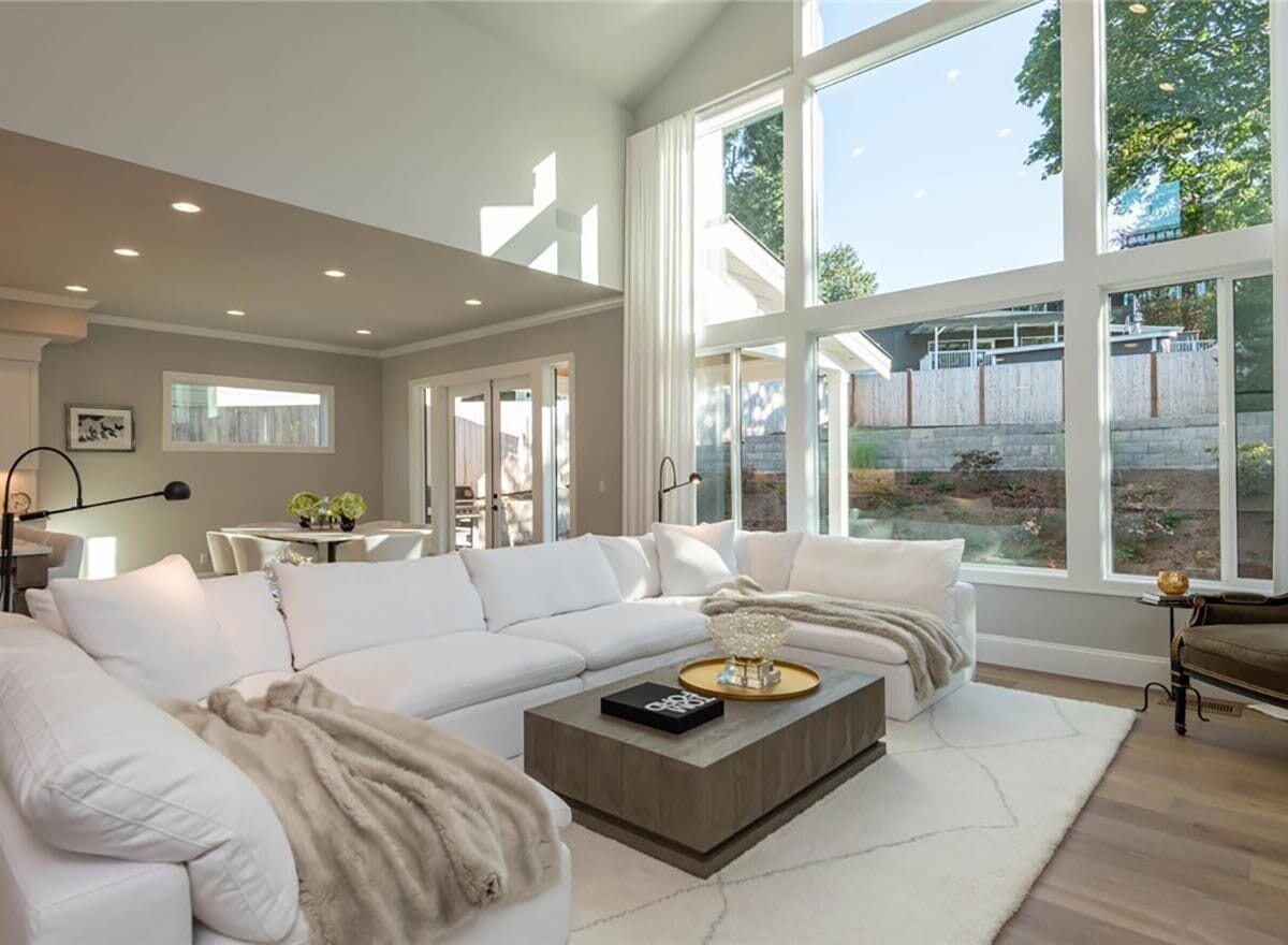 Great room with a large sectional sofa, a wooden coffee table, and a wall of windows overlooking the backyard.