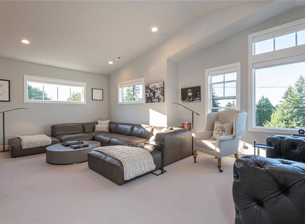 Media room with a leather sofa and mismatched chairs under a vaulted ceiling.