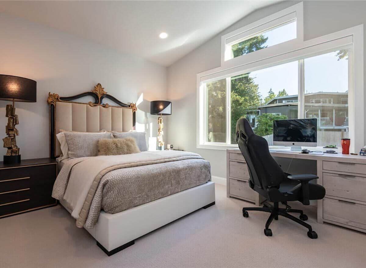 Bedroom with an ornate bed and a distressed desk against the windows.