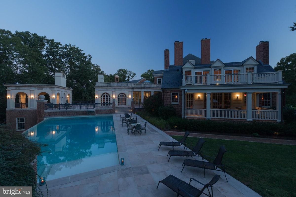 Night-shot of the pool with lounge chairs and tables.