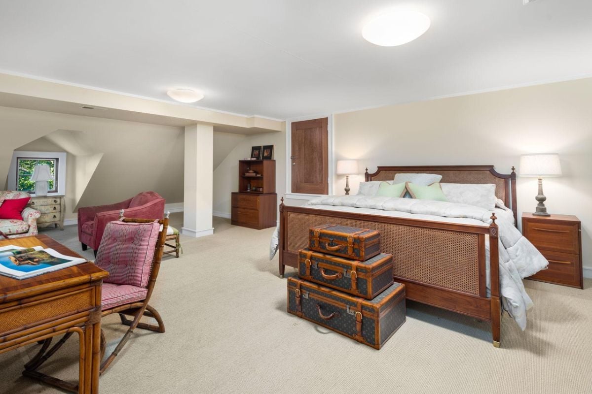 Bedroom with a large bed, carpet flooring, desk and chairs.