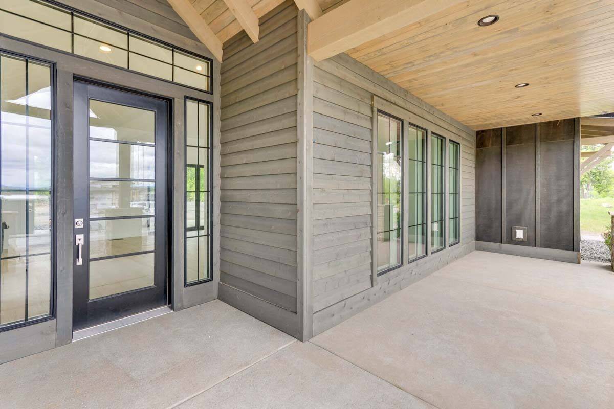 Front porch with wood-paneled ceiling and a glazed entry door.
