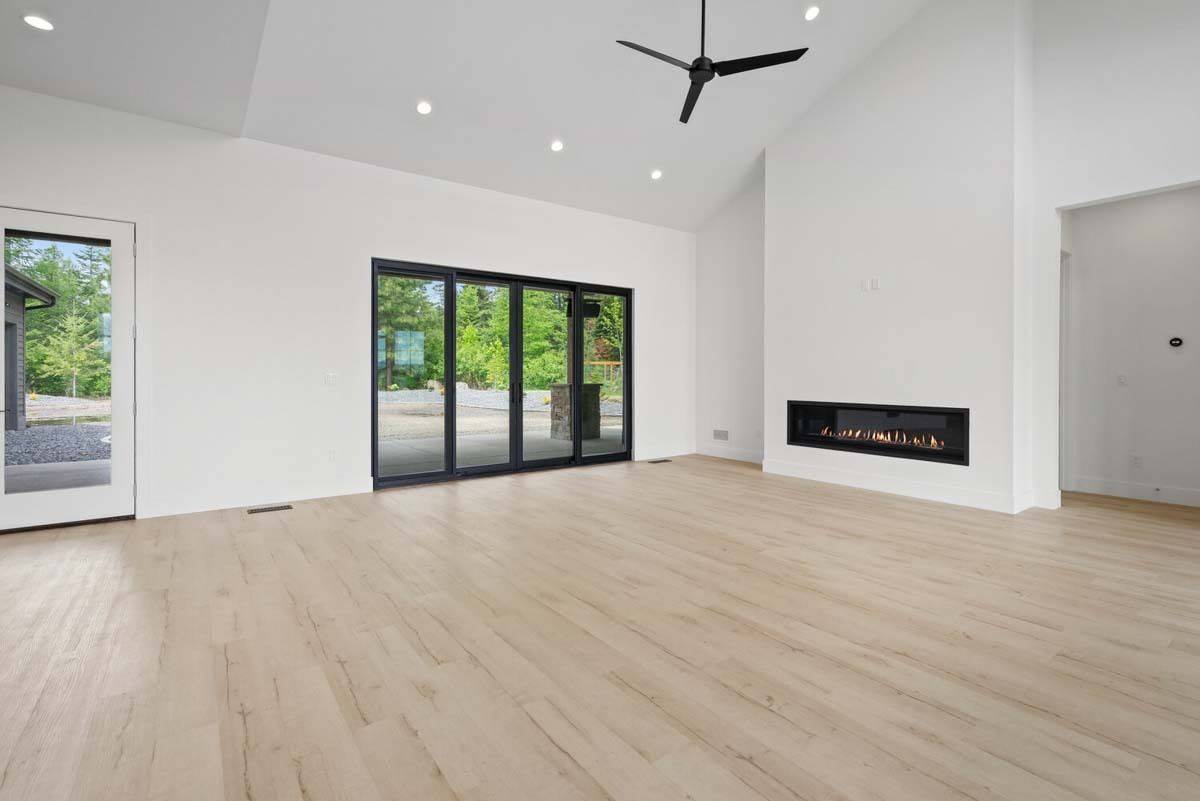 Living room with a linear fireplace, a vaulted ceiling, and sliding glass doors that open to the rear porch.