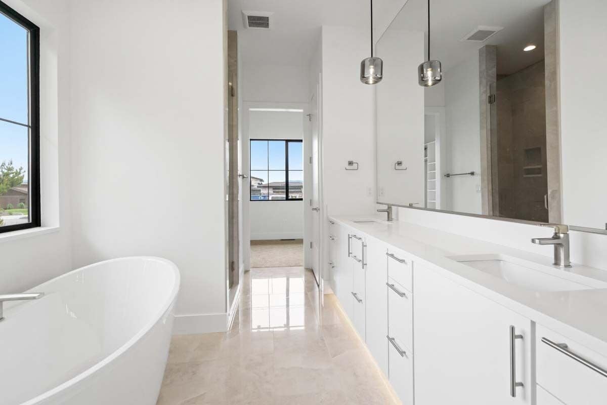 Primary bathroom with a dual sink vanity and a soaking tub over the marble-tiled flooring.