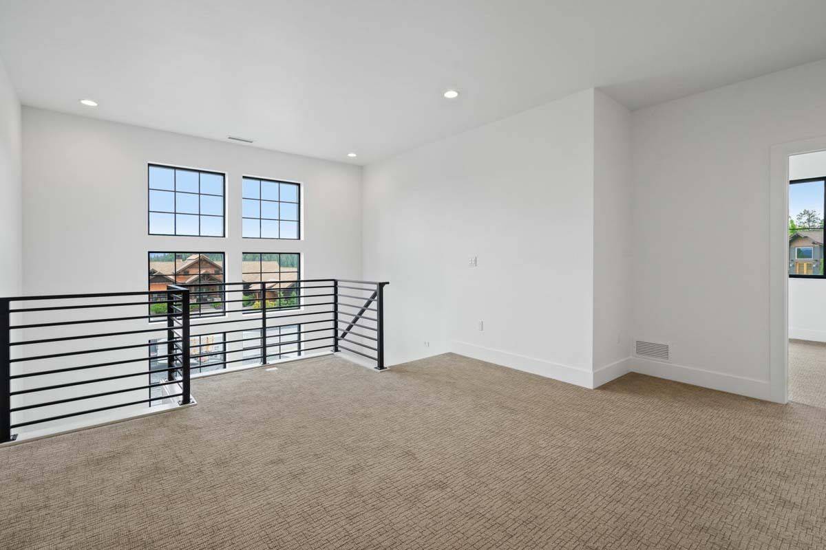 Loft with a carpeted floor and wrought iron railings.