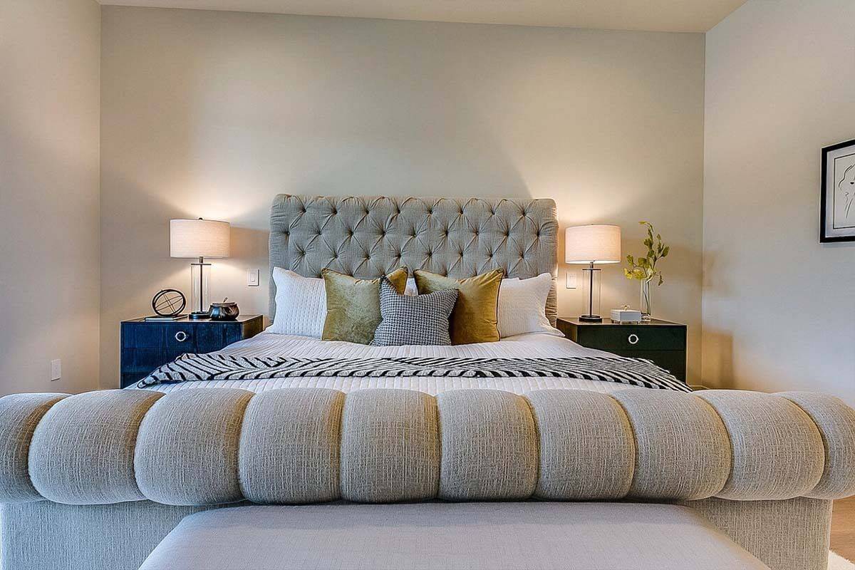 Primary bedroom with a tufted bed flanked by deep blue nightstands.