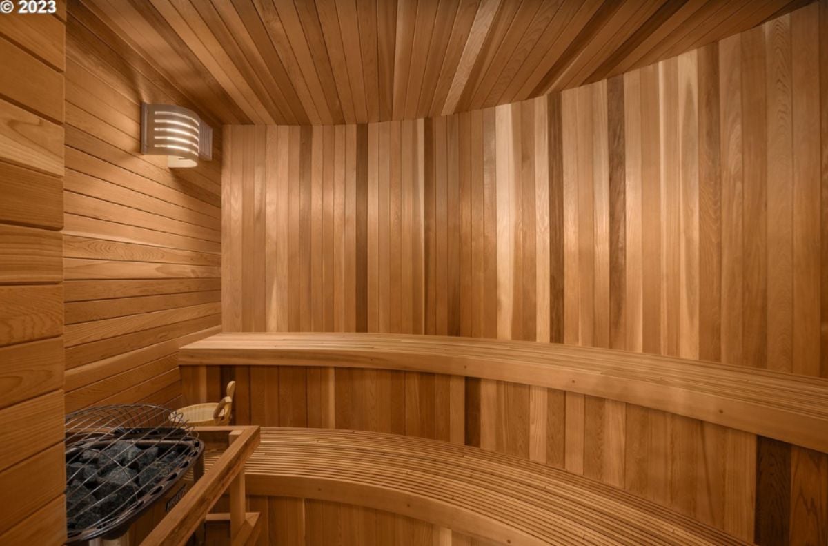 Sauna room with a wooden wall and a light fixture.