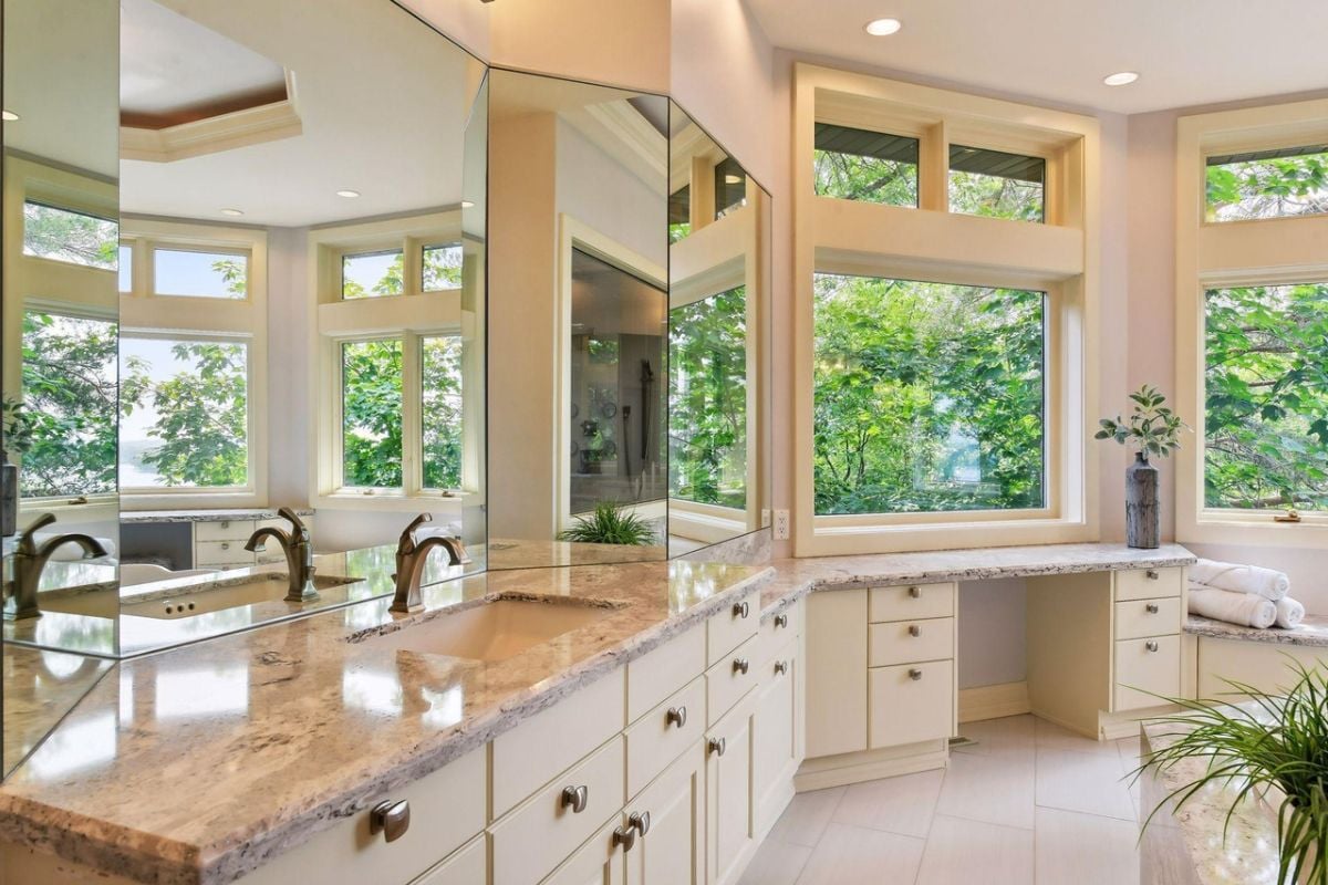 Bathroom with wooden white vanity and large mirrors.