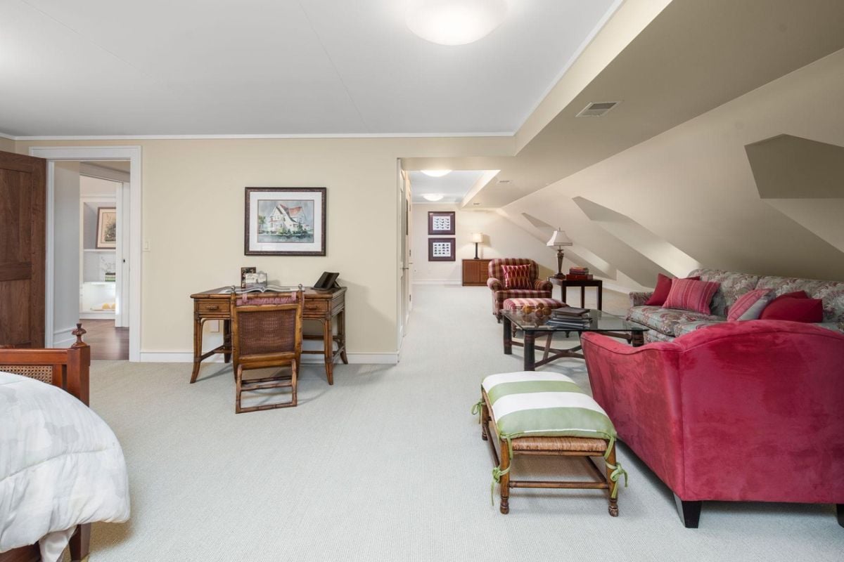 Bedroom with a large bed, carpet flooring, desk, chairs, and couches.