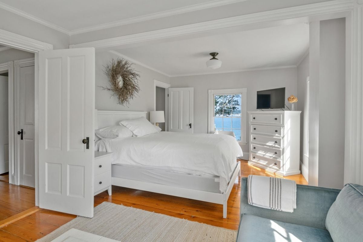 Bedroom with a large bed, TV, glass window and a wooden door.