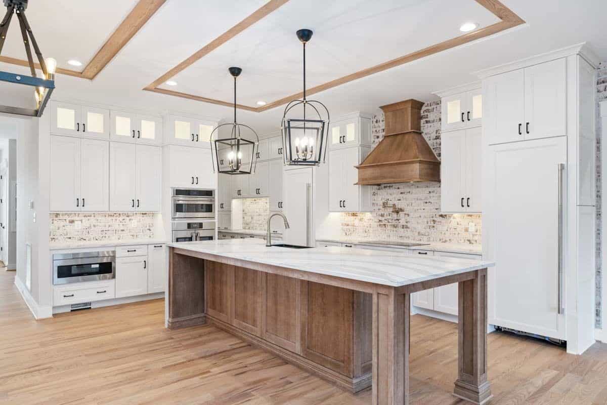 Kitchen with white cabinetry, stainless steel appliances, and a center island with a prep sink.