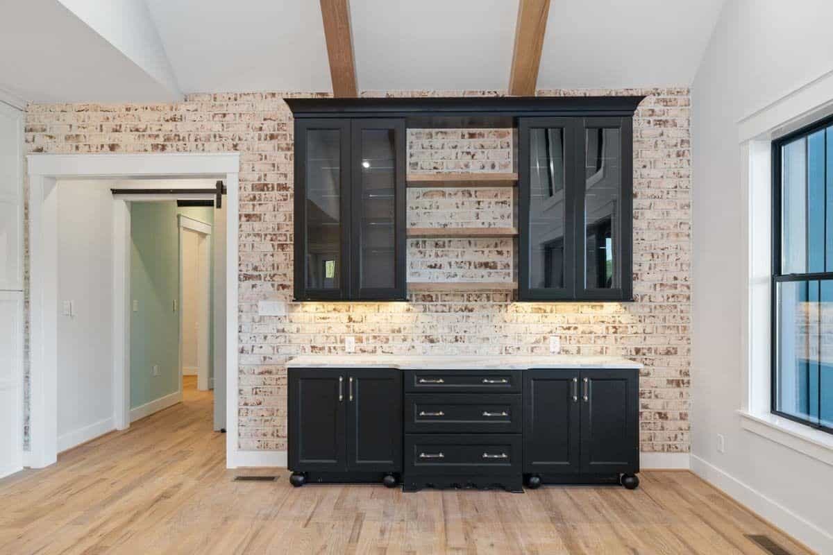 Dining room with black cabinets, floating shelves, and a brick accent wall.