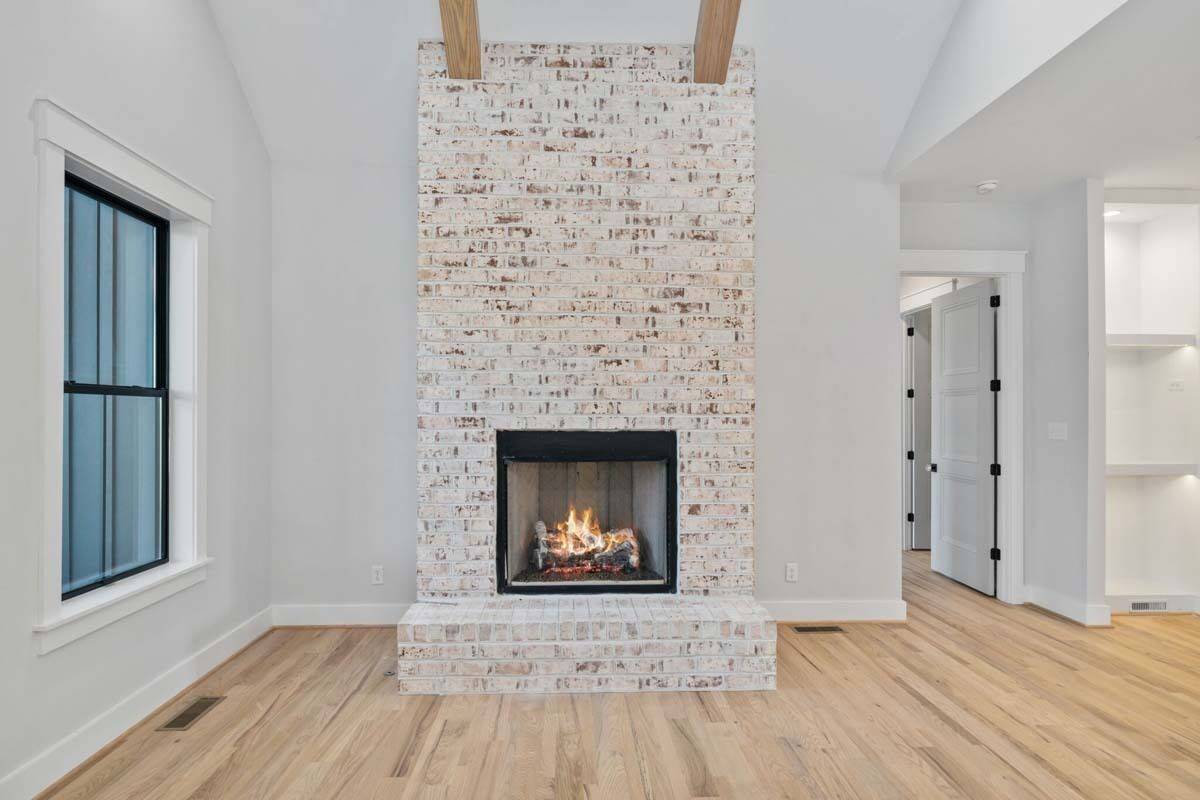Living room with a brick fireplace and a vaulted ceiling accentuated with exposed beams.
