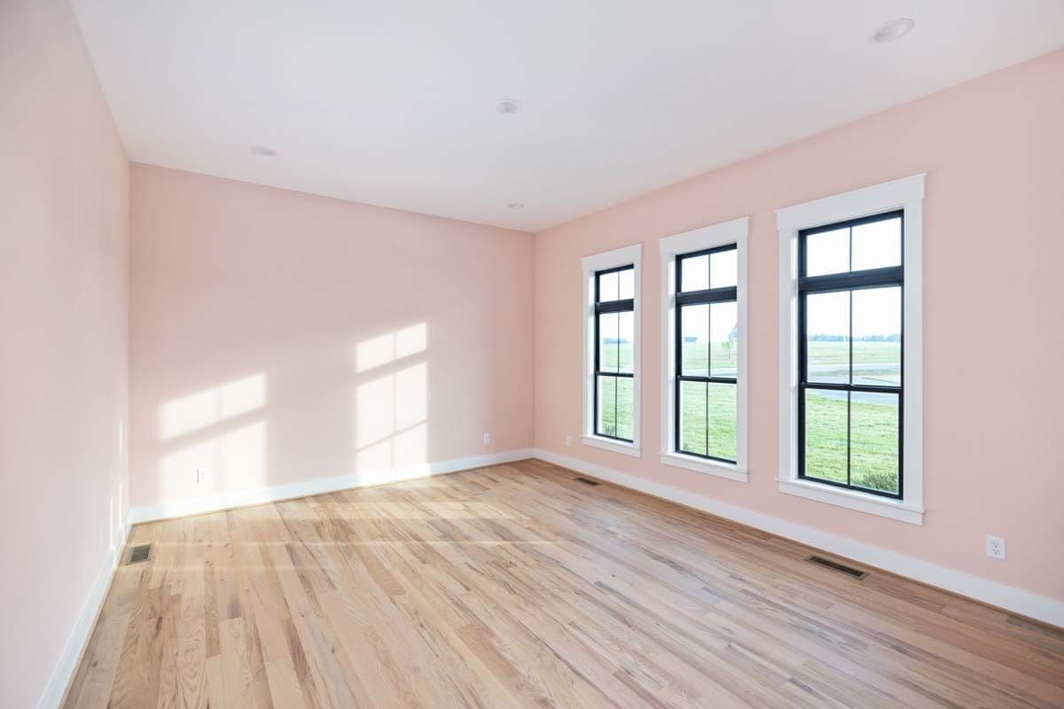Bedroom with light pink walls and hardwood flooring.