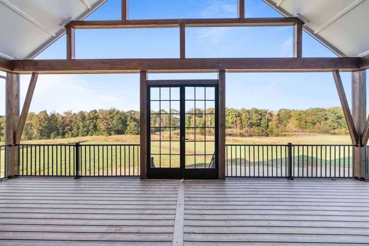 Screened porch with wide plank flooring, wrought iron railings, and a French door.