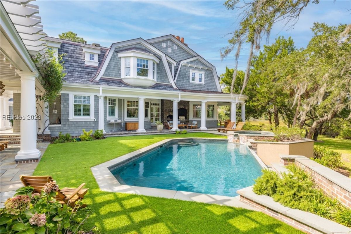 Pool with lounge chairs and green lawn.