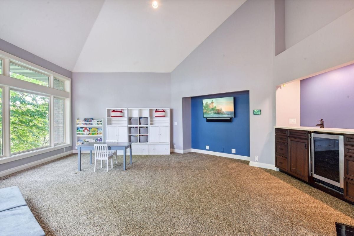 Kid's playroom with carpet flooring, TV, small table and chair.
