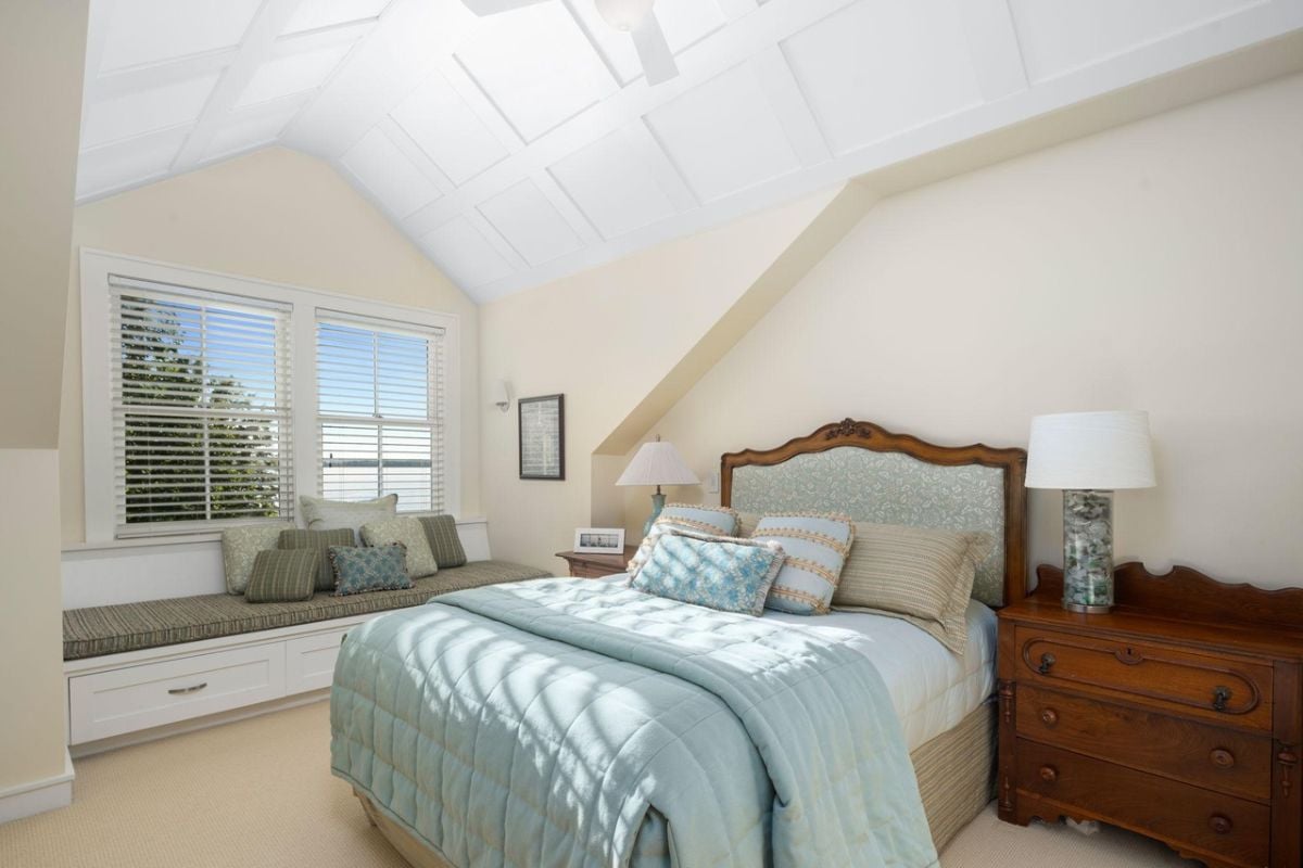 Bedroom with a large bed, carpet flooring and glass windows.