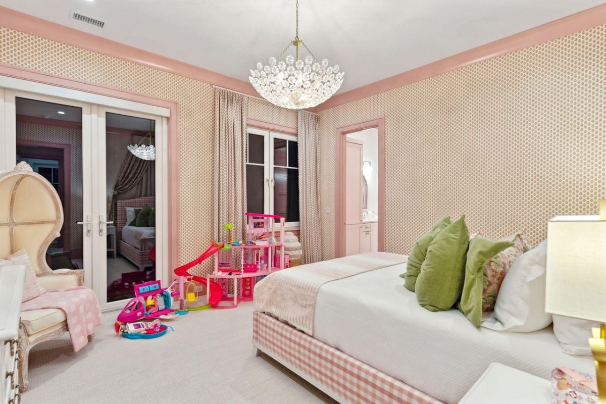 Bedroom with a large bed, carpet flooring, chandelier and glass door.