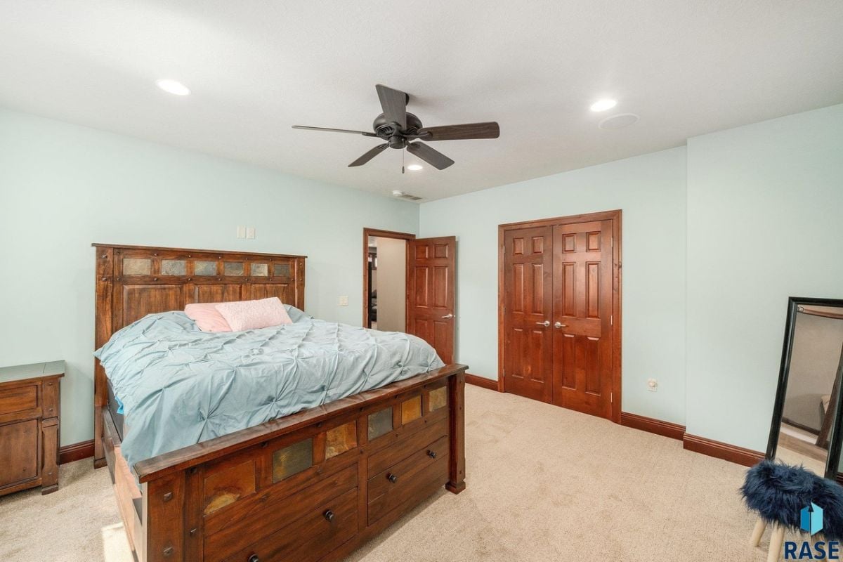 Bedroom with a large bed, carpet flooring, and a ceiling fan.
