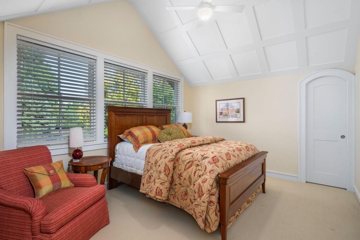 Bedroom with a large bed, couch, carpet flooring and glass windows.