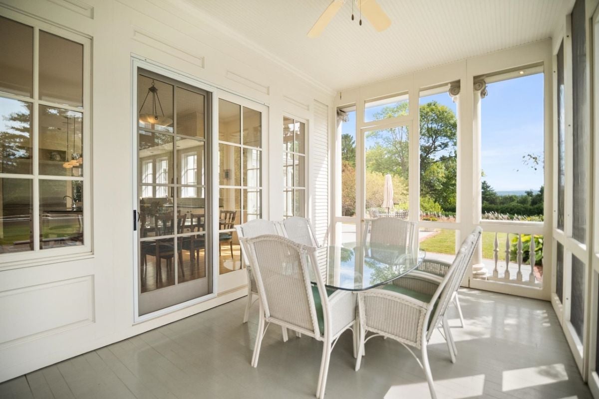 Screened porch with a table and chairs.