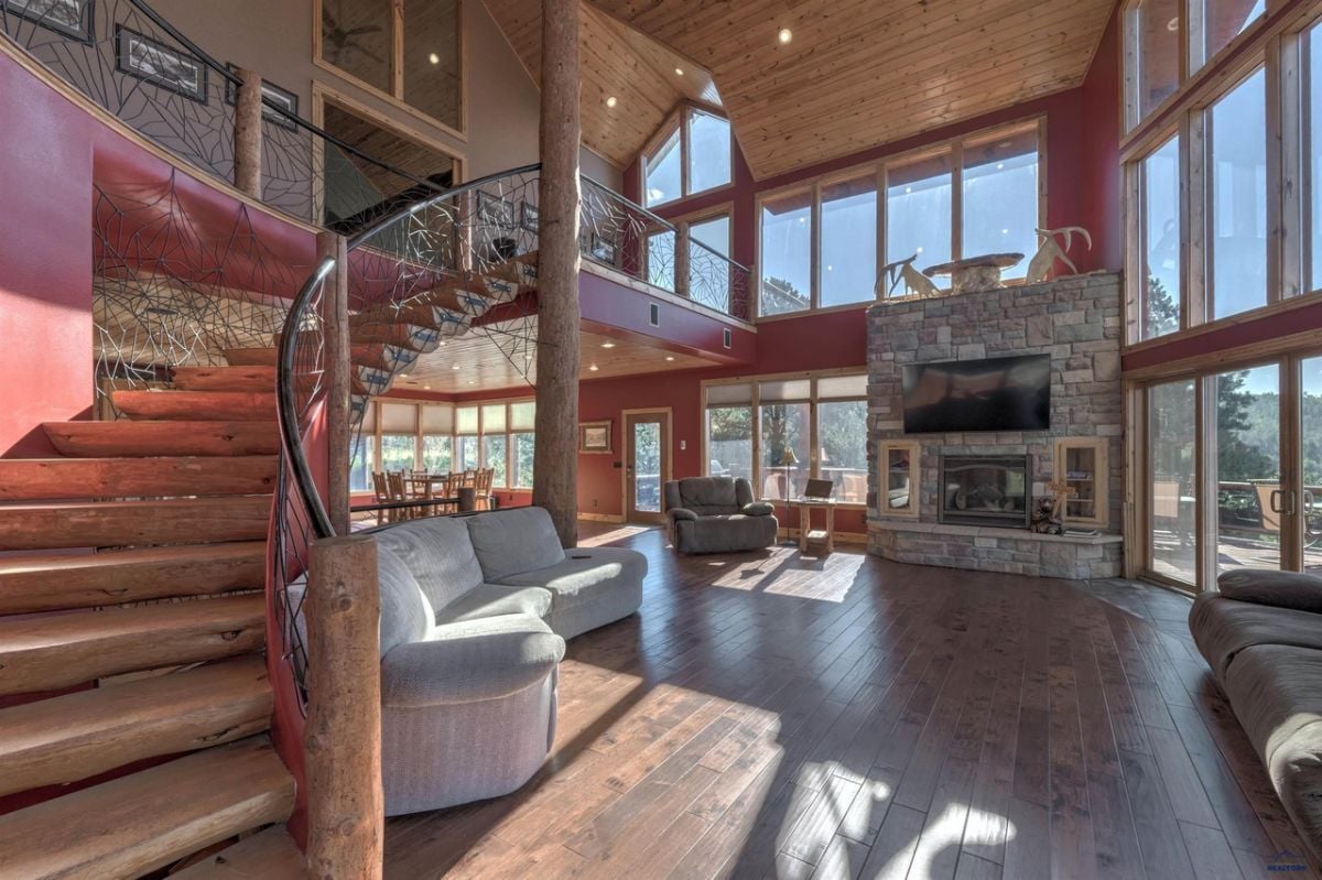 Living room with couches, staircase, TV, glass walls and a fireplace.
