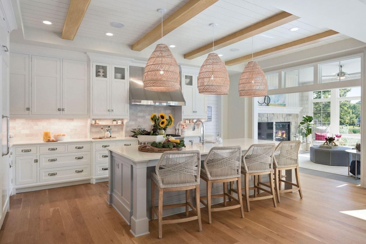Kitchen with a large island, open beam ceiling, custom lights, custom cabinets and wood flooring.
